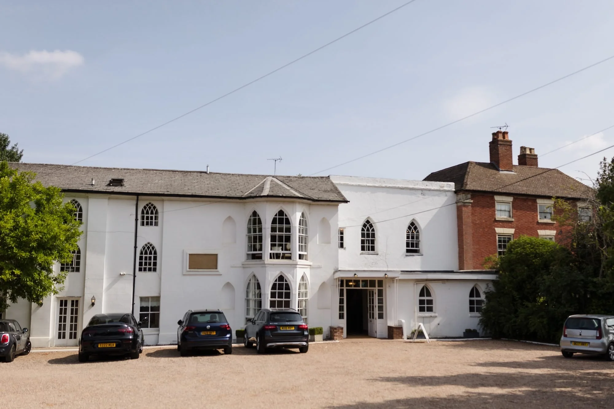 The white front of Warwick House in Southam, with its arched Gothic windows and gravel driveway