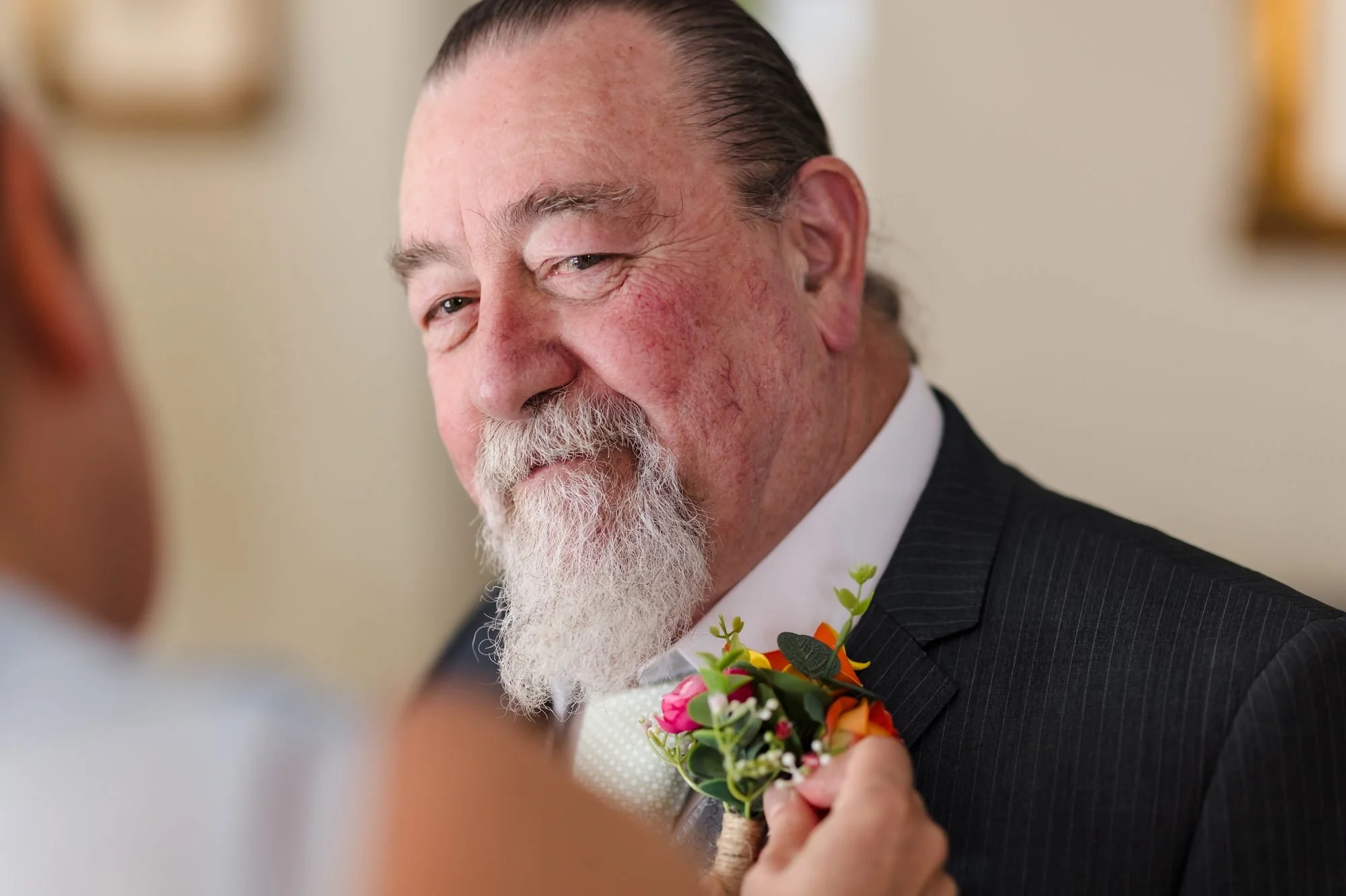 Father of the bride smiling as his buttonhole is pinned on before the wedding at Warwick House