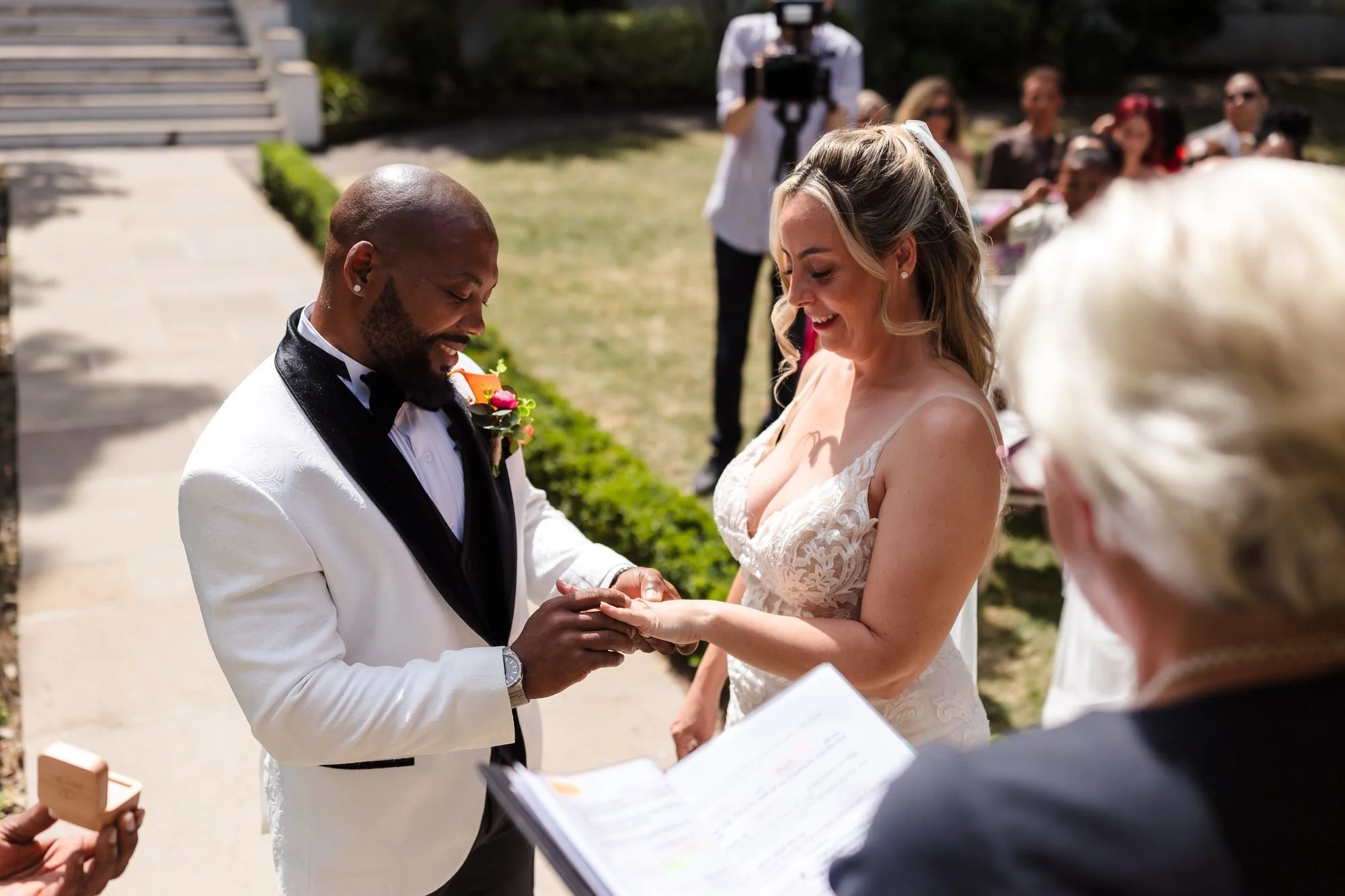 Tafarie placing the ring on Angela's finger during their outdoor ceremony in full sun at Warwick House