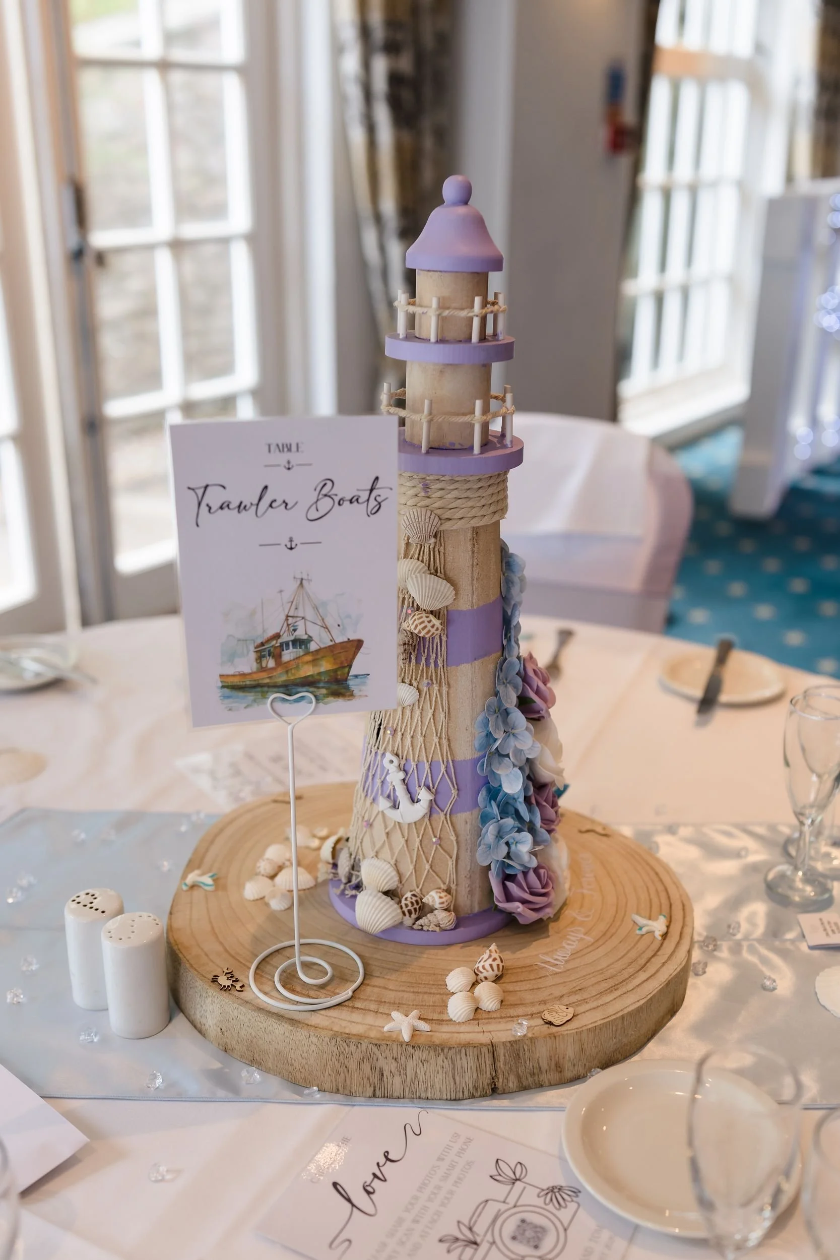 Lilac lighthouse table centrepiece and Trawler Boats table name at a coastal wedding at Berry Head Hotel