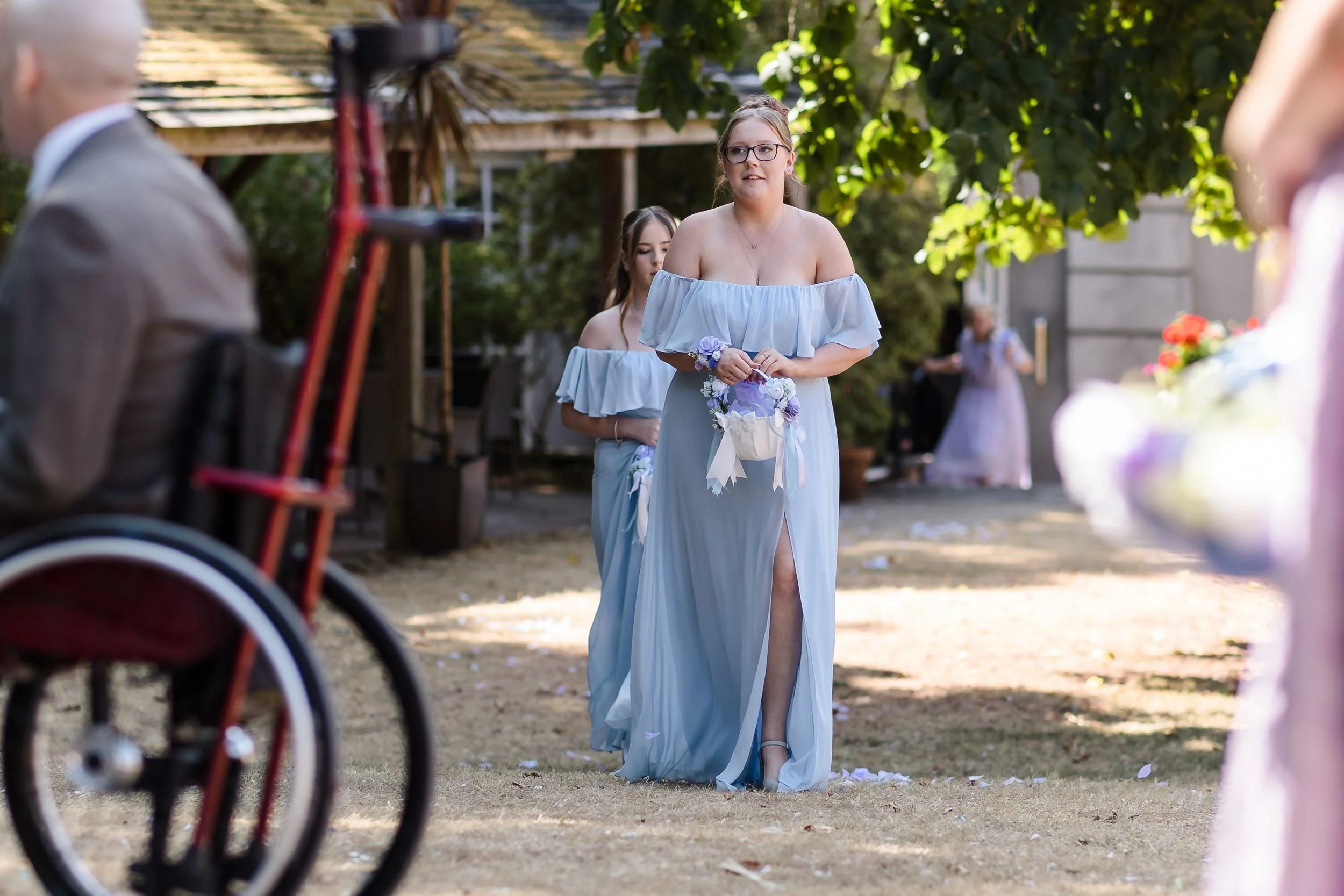 Bridesmaids walk down the aisle to the outdoor wedding ceremony in the walled garden at Berry Head Hotel