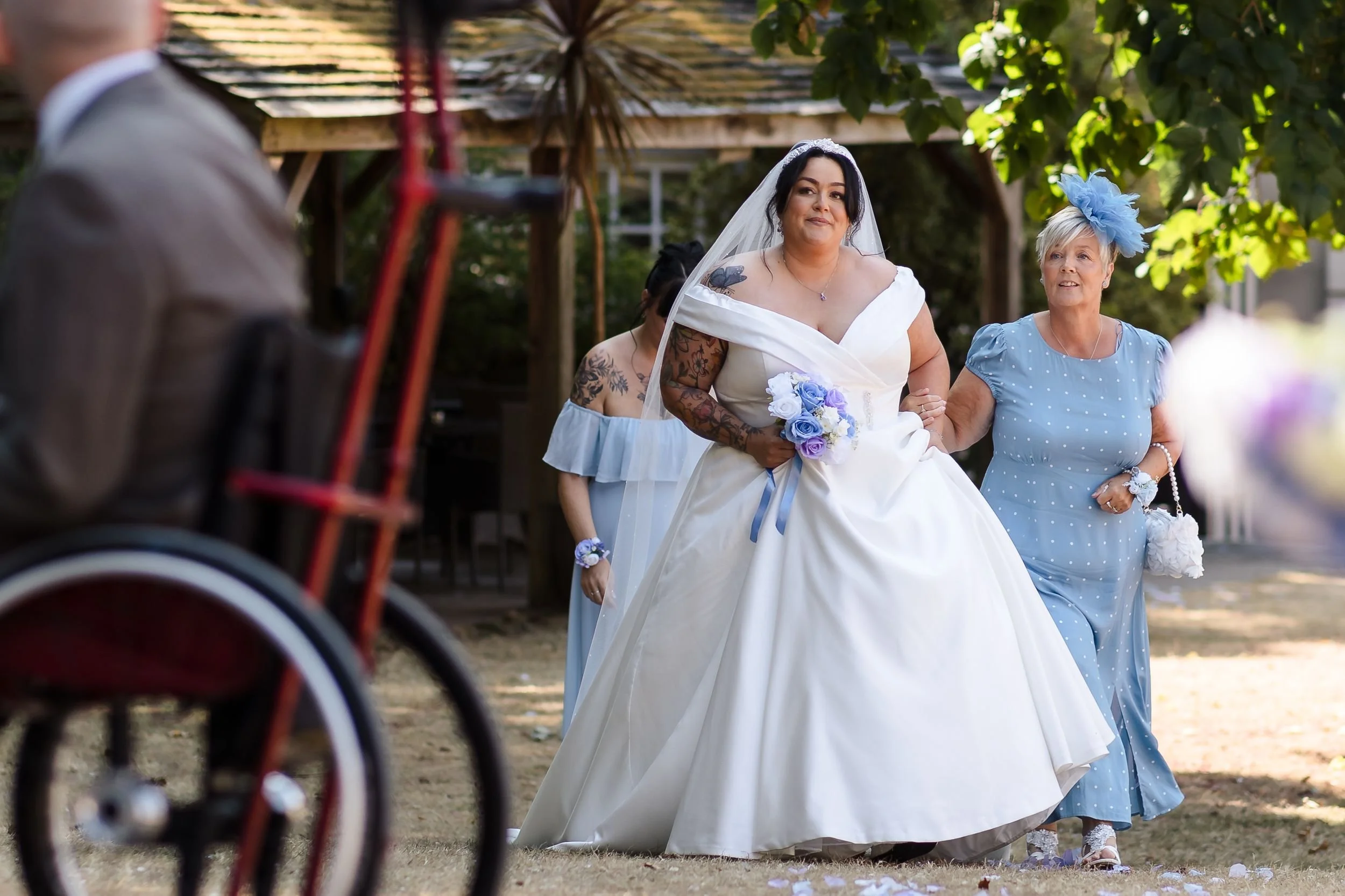 Bride walks down the aisle arm in arm with a family member at her outdoor ceremony at Berry Head Hotel