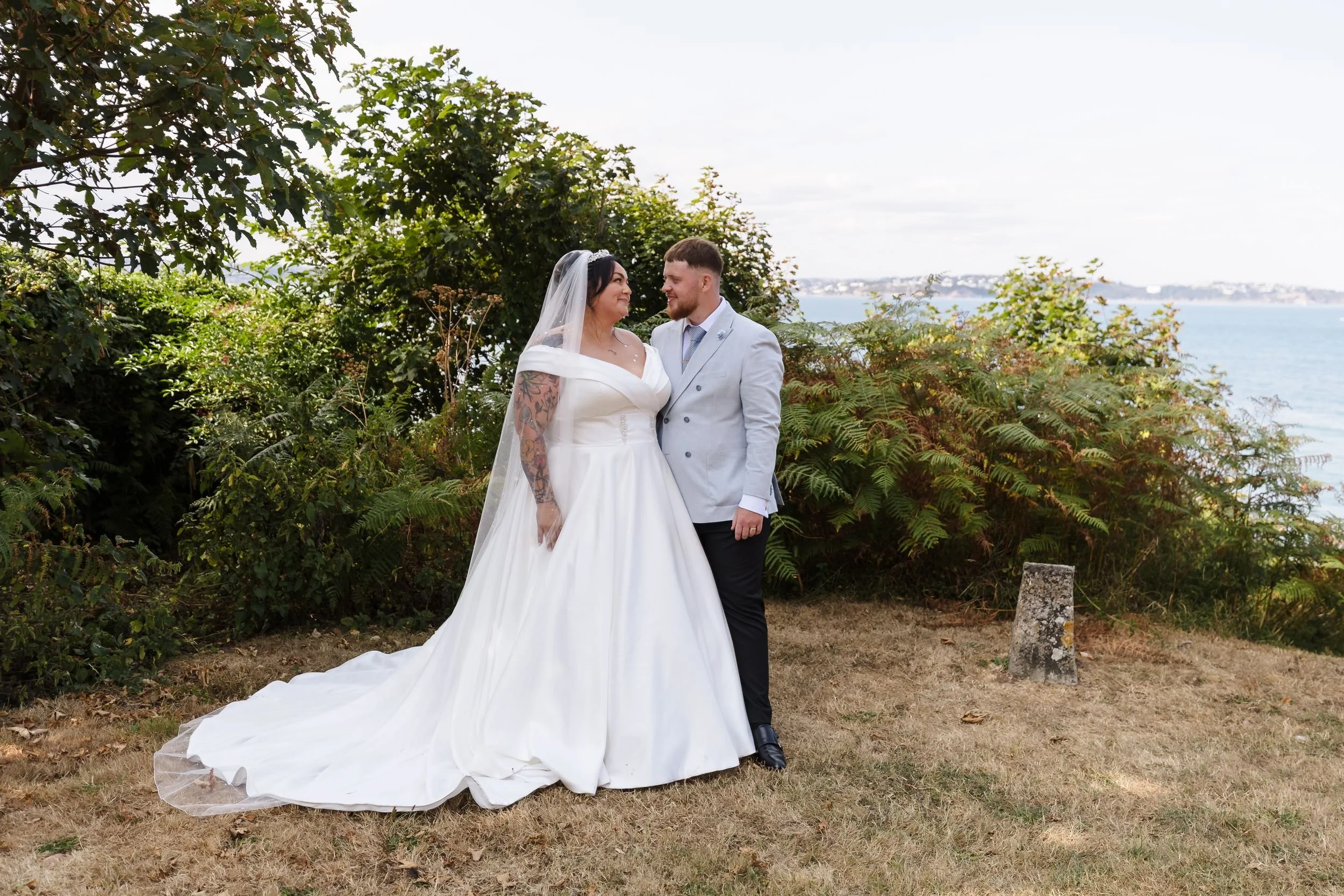 Bride and groom portrait on the lawn at Berry Head Hotel, the bride's train spread out and the sea beyond