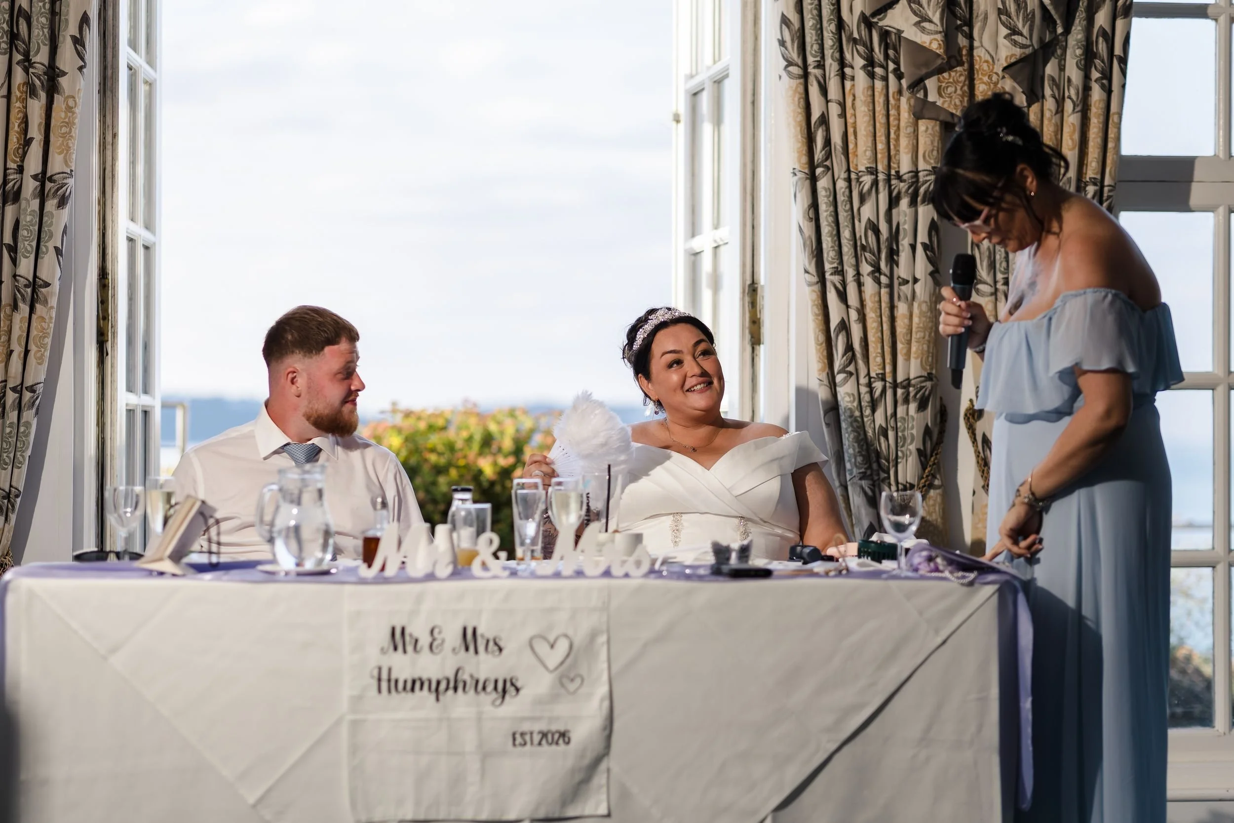 Bridesmaid gives a speech beside the Mr and Mrs sweetheart table at Berry Head Hotel, lit with off-camera flash