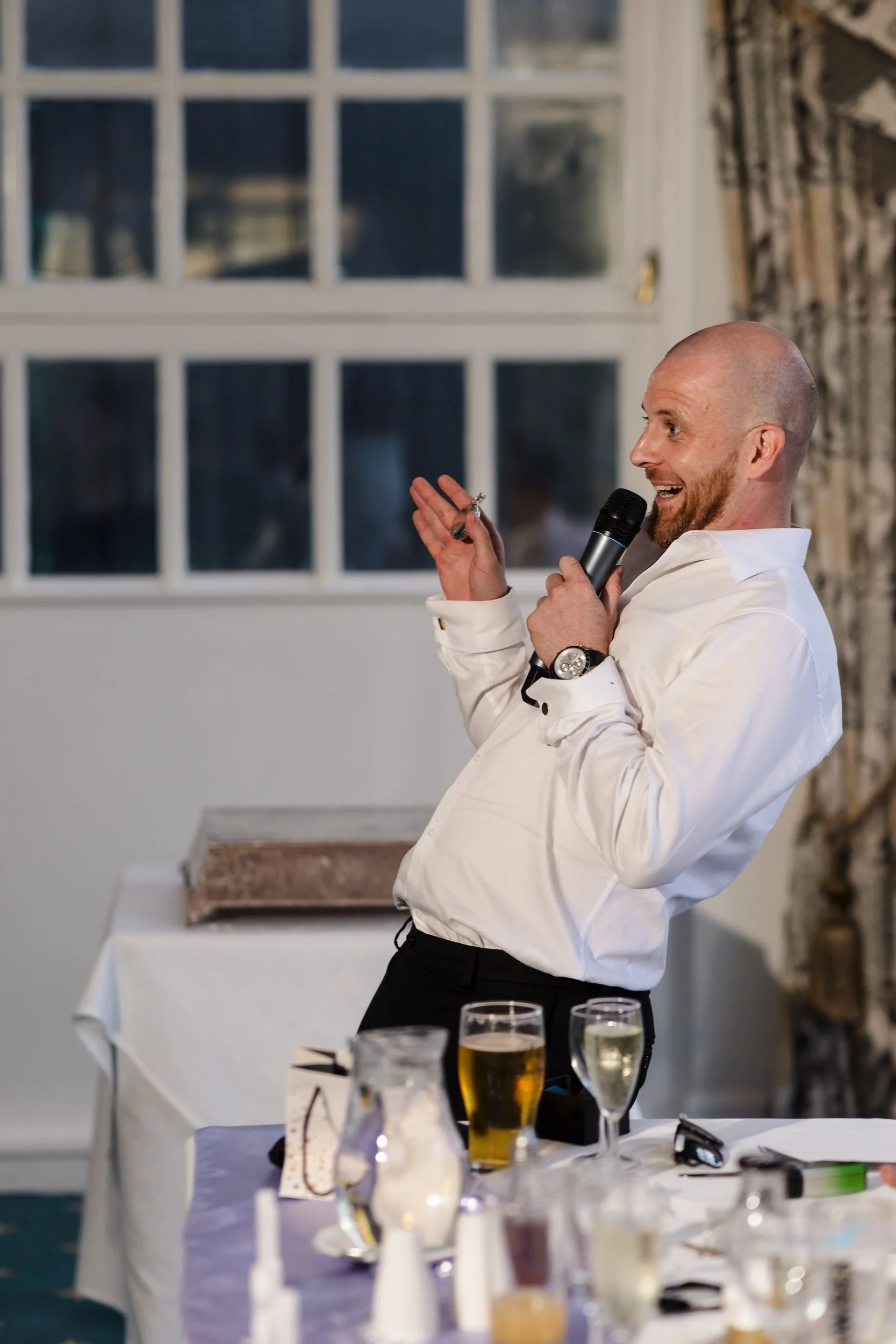 Best man gestures with the microphone during his speech in the Mulberry Room at Berry Head Hotel