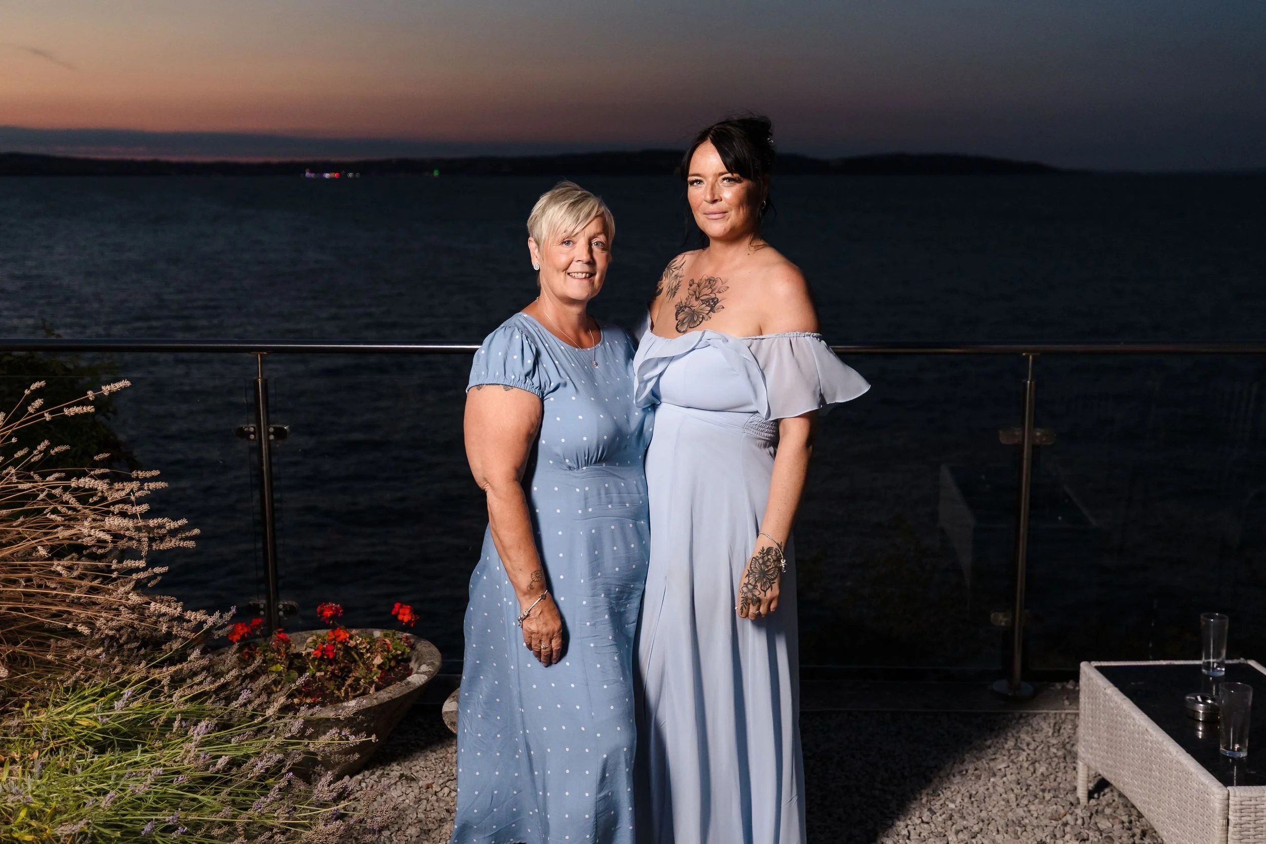 Two wedding guests photographed on the deck at Berry Head Hotel with the last evening colour over the bay