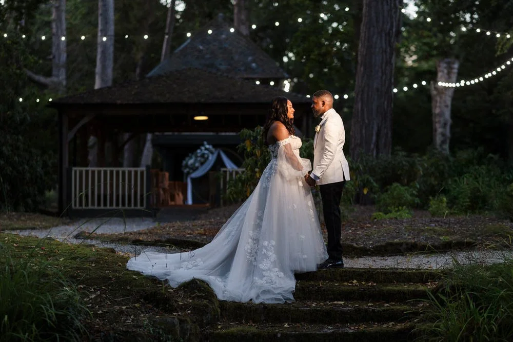 Bride and groom on the island steps at dusk at Hogarths Hotel Solihull, fairy lights overhead and the treehouse pavilion behind — evening wedding photography by Once in a Lifetime Photography, Worcestershire
