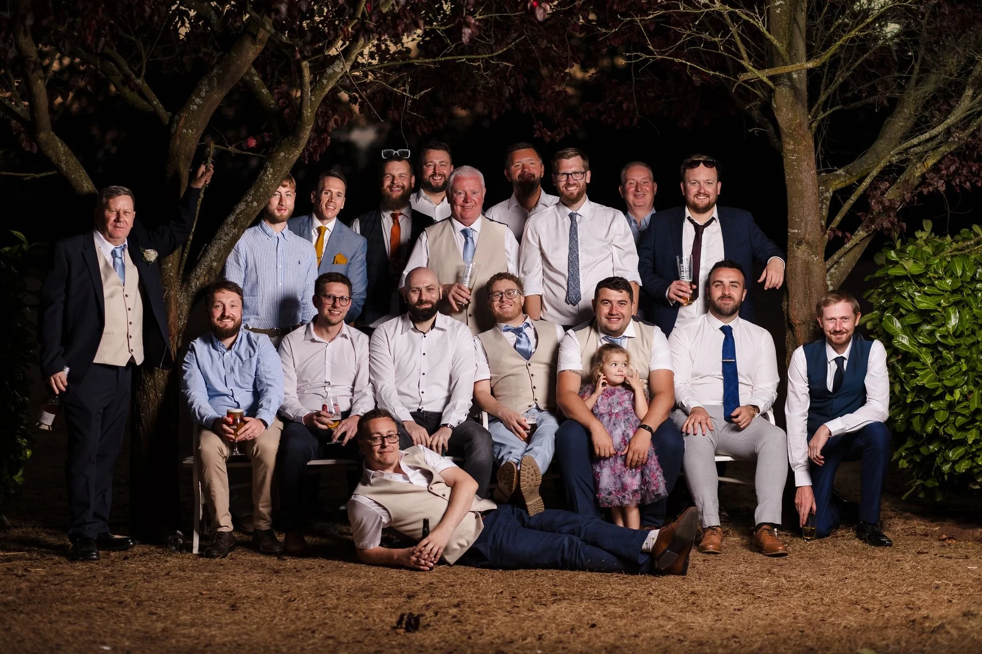 Josh's friends and family gathered for a flash-lit group portrait under the trees after dark