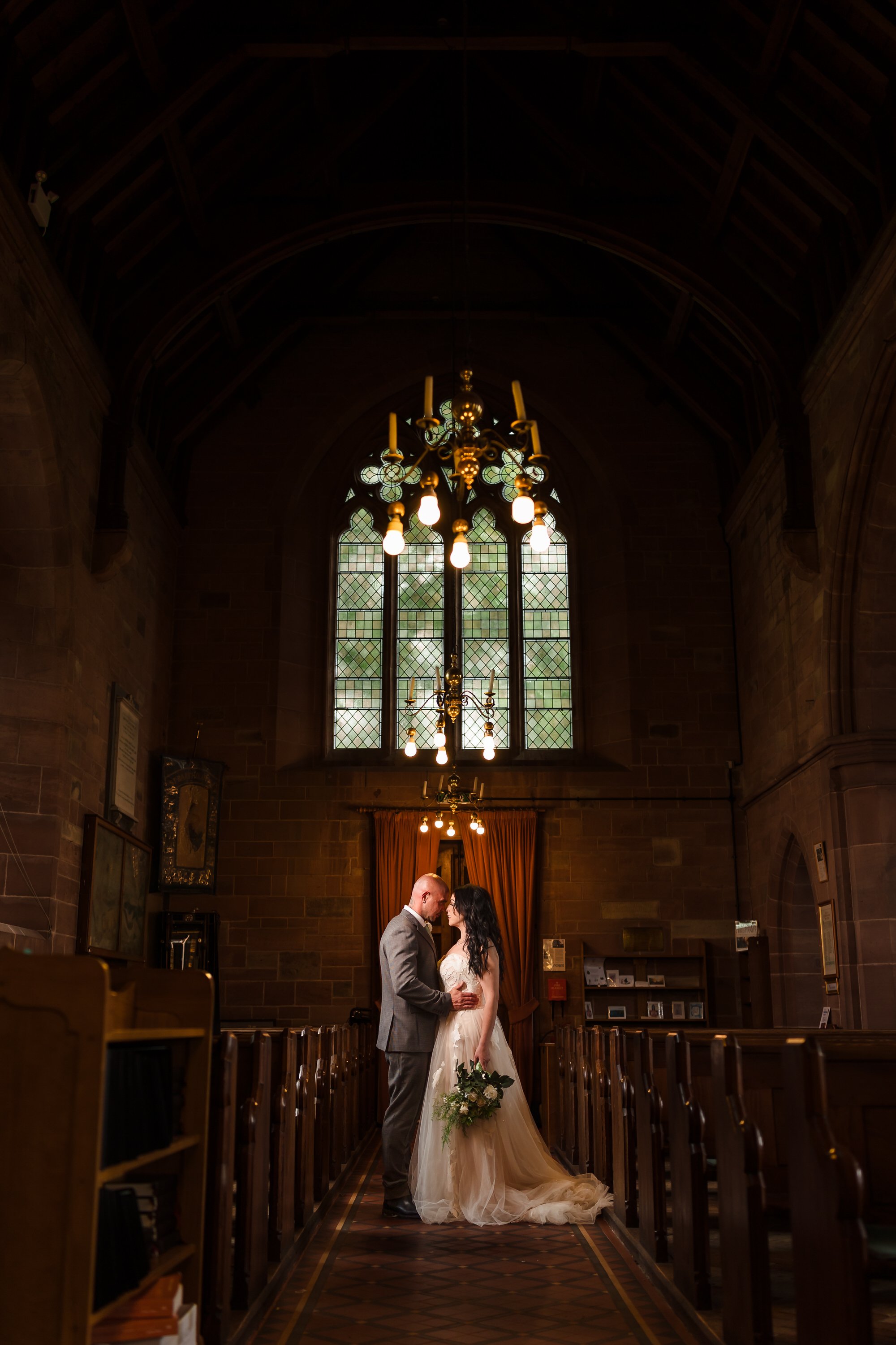 Bride and groom embracing beneath a chandelier at St Bartholomew's Church, Stourport wedding photography.
