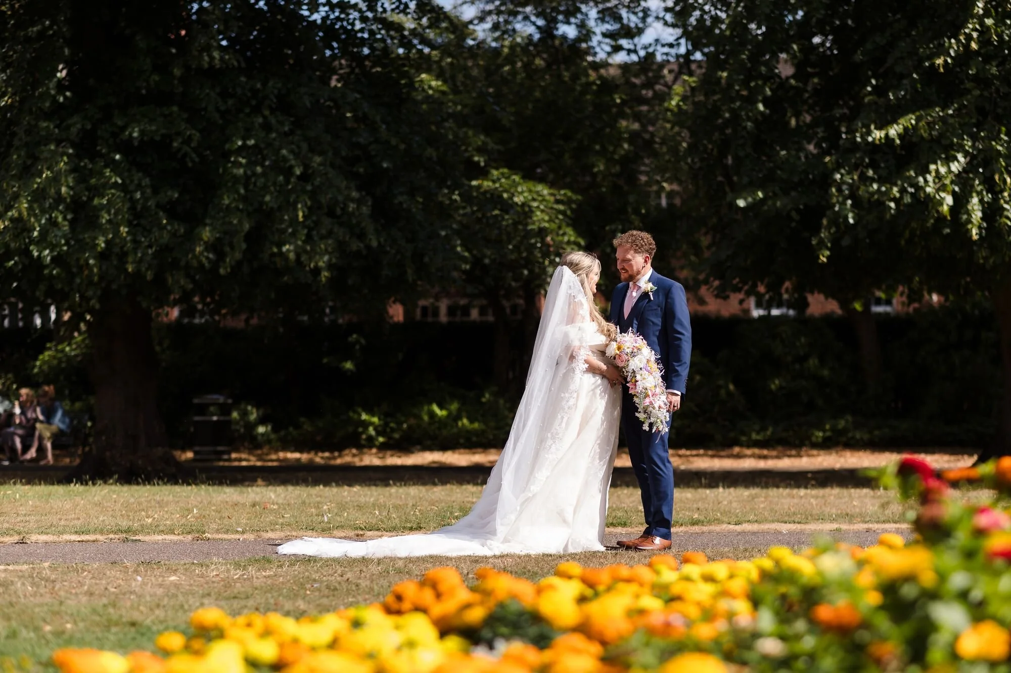 The couple photographed through the flower beds in Museum Gardens, Lichfield, wedding photography by Once in a Lifetime Photography.