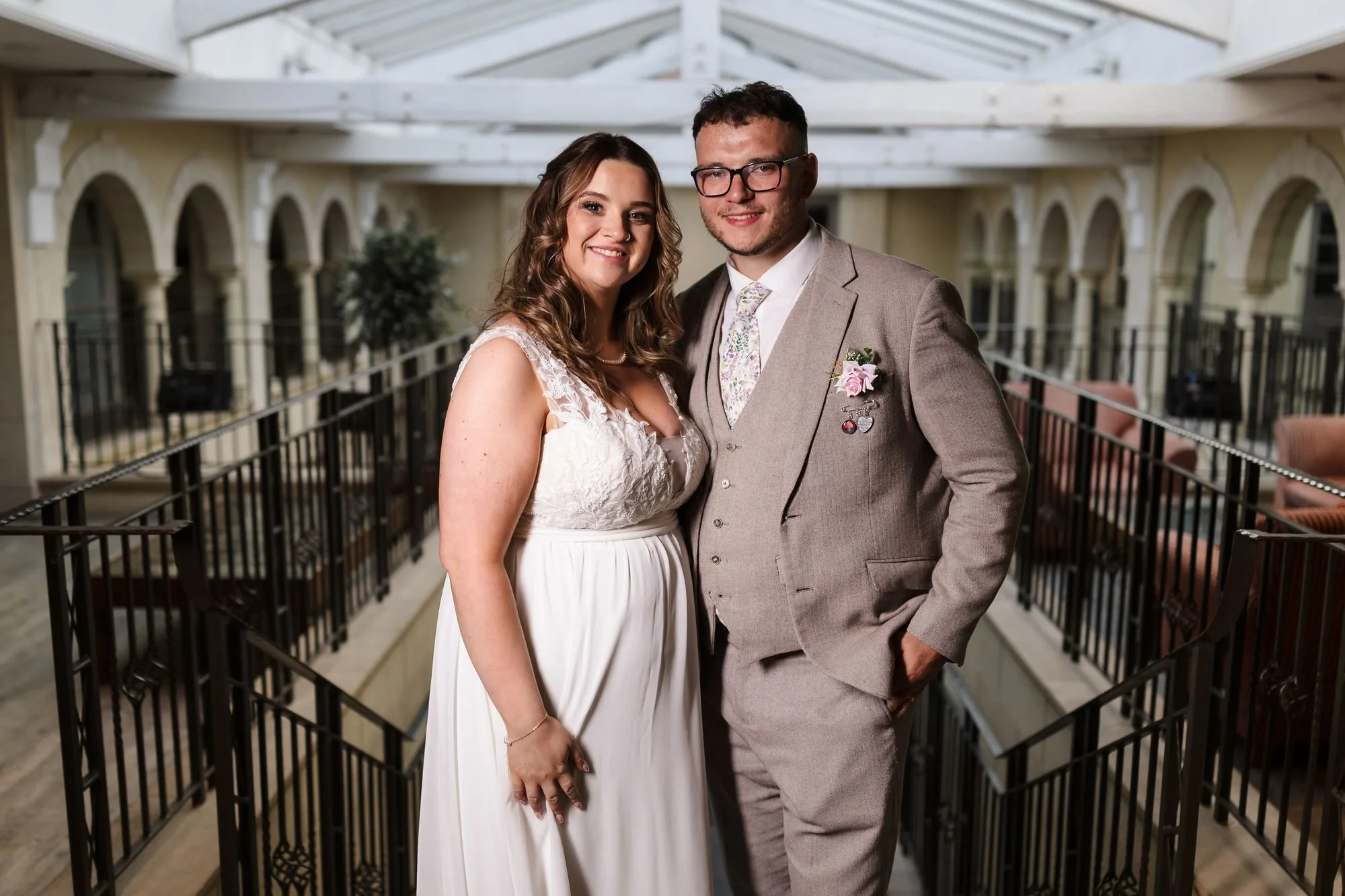 Holly and Dan posing at the top of the staircase at Nailcote Hall, lit by off-camera flash with the arched balconies behind them