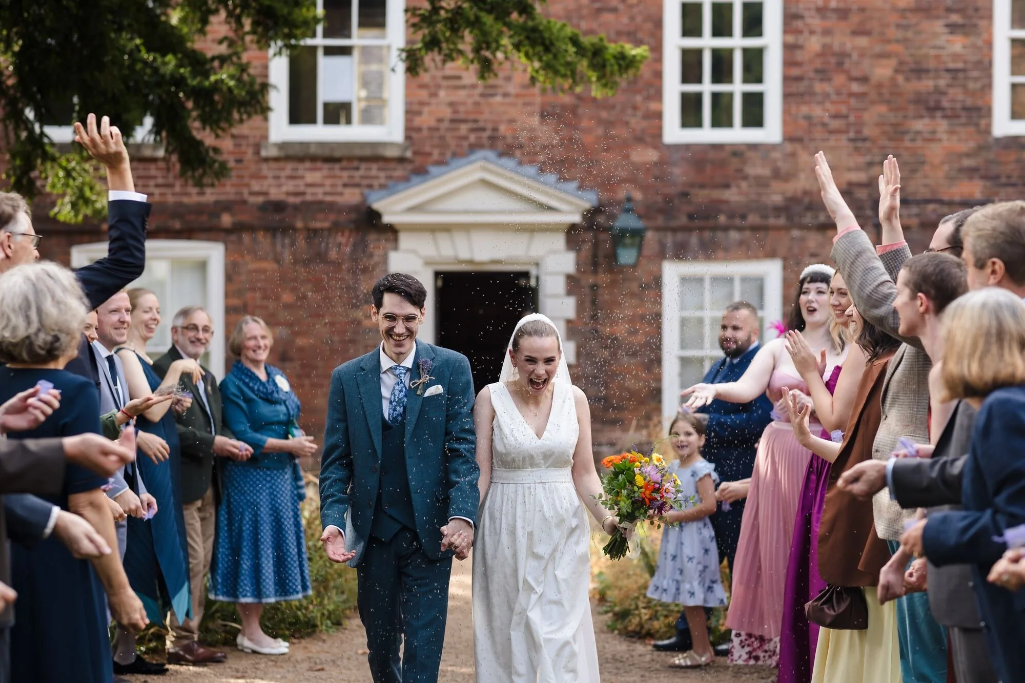Isabelle and Chris walking through a confetti line of cheering guests in the garden at The Commandery, Worcester, by Once in a Lifetime Photography