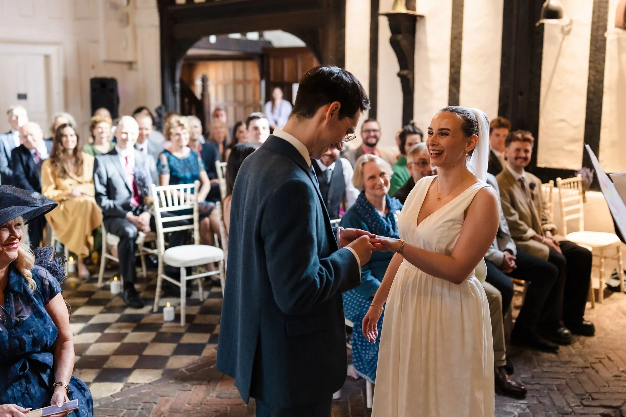 Isabelle laughing as Chris places her ring during their ceremony in the Great Hall at The Commandery, Worcester, by Once in a Lifetime Photography