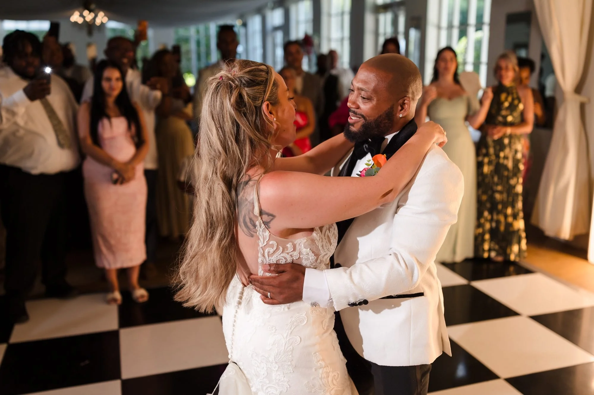 Bride and groom's first dance on the black and white dance floor as guests look on at Warwick House