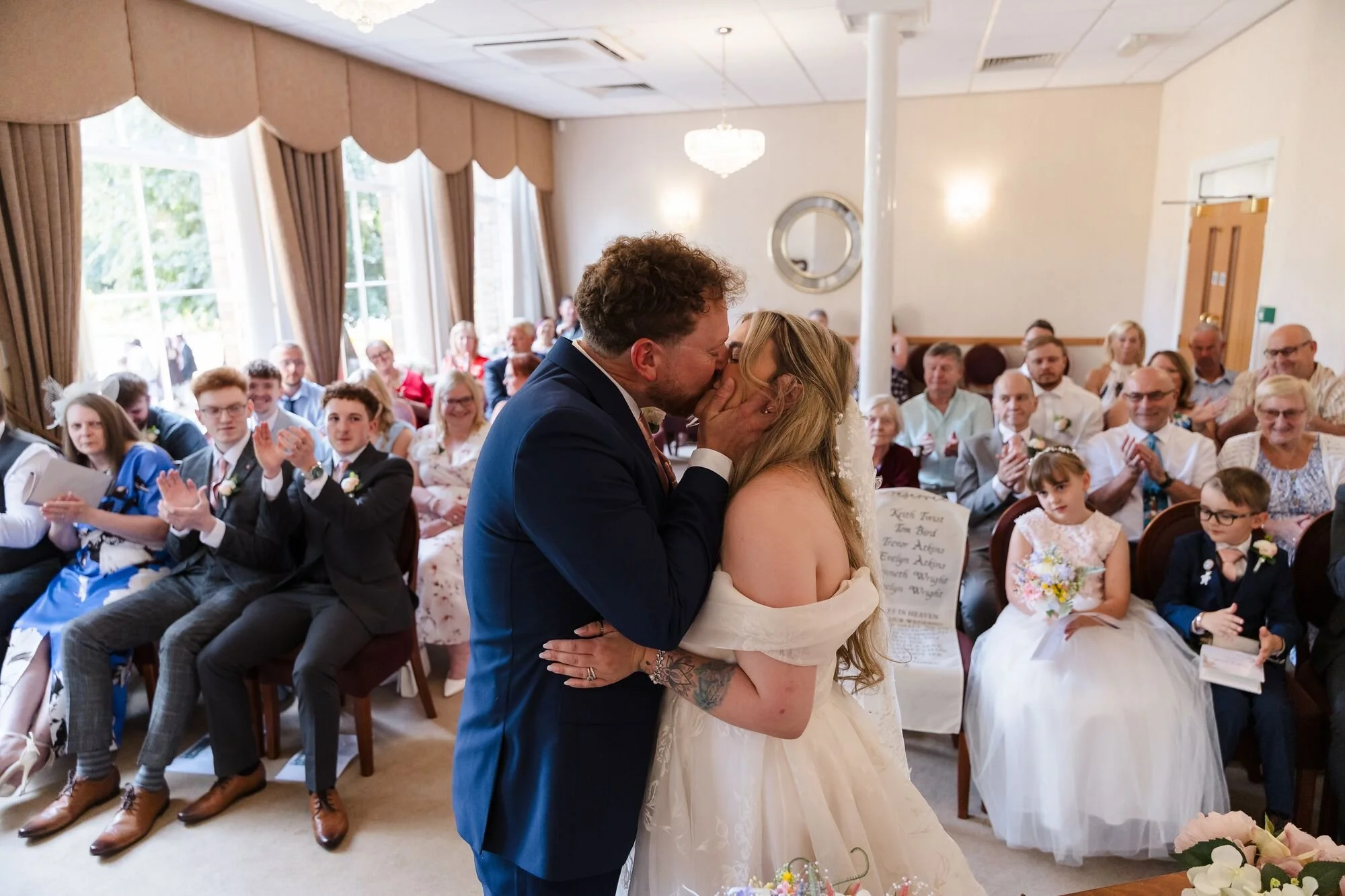 The first kiss as guests applaud at Lichfield Registry Office, wedding photography by Once in a Lifetime Photography.