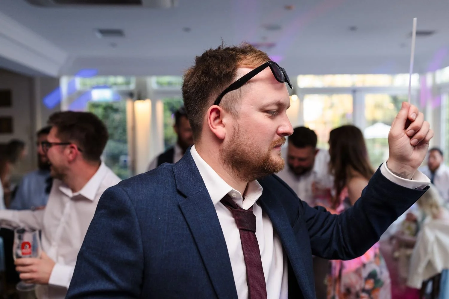 A guest with sunglasses on his head waving an illuminated baton on the dance floor