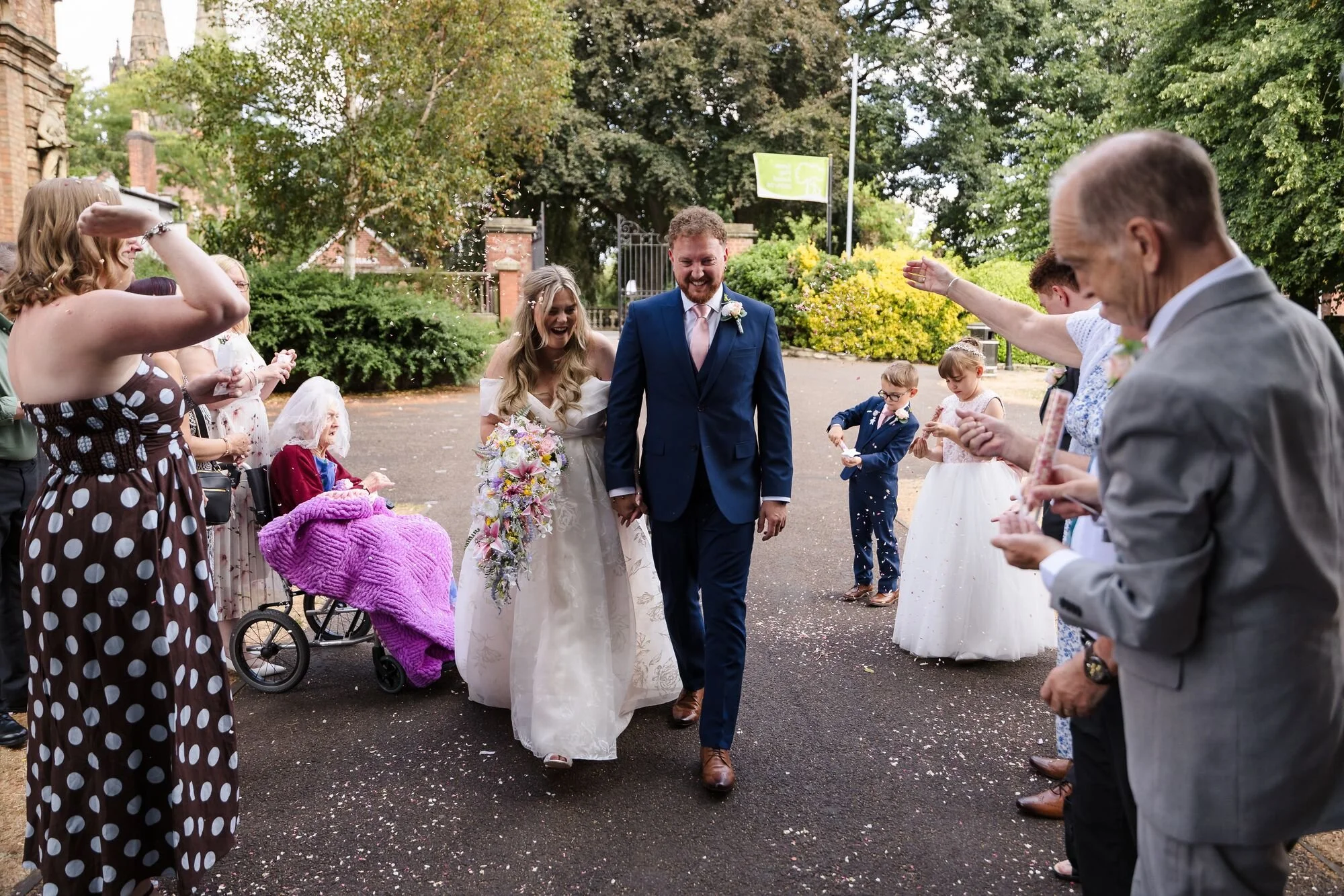 Guests throwing confetti as the couple walk out into Museum Gardens at Lichfield Registry Office, wedding photography by Once in a Lifetime Photography.