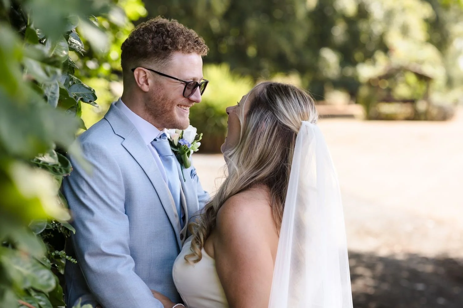 Cheryl and Josh laughing face to face in dappled shade in the gardens