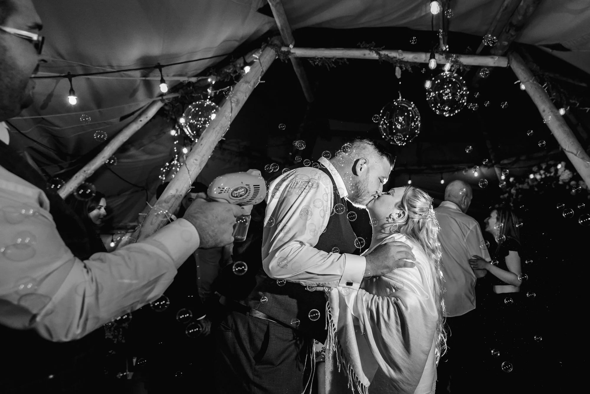 Bride and Groom Kissing in a tipi wedding with bubbles