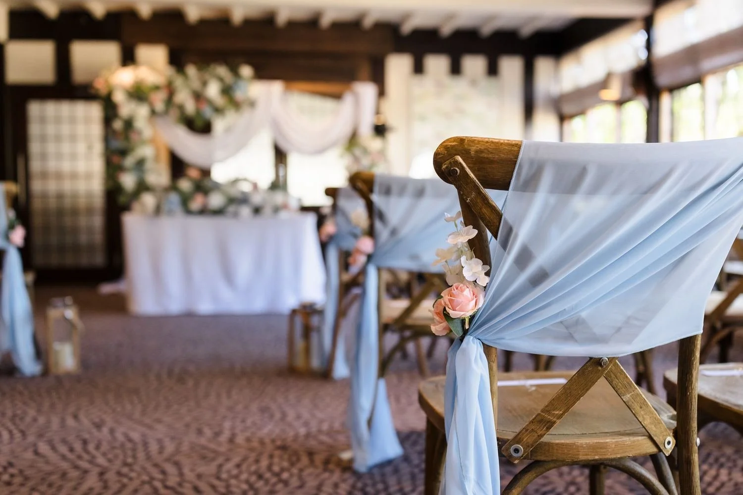 Close-up of a sky-blue chair drape with a pink rose on a wooden cross-back chair in the Drawing Room