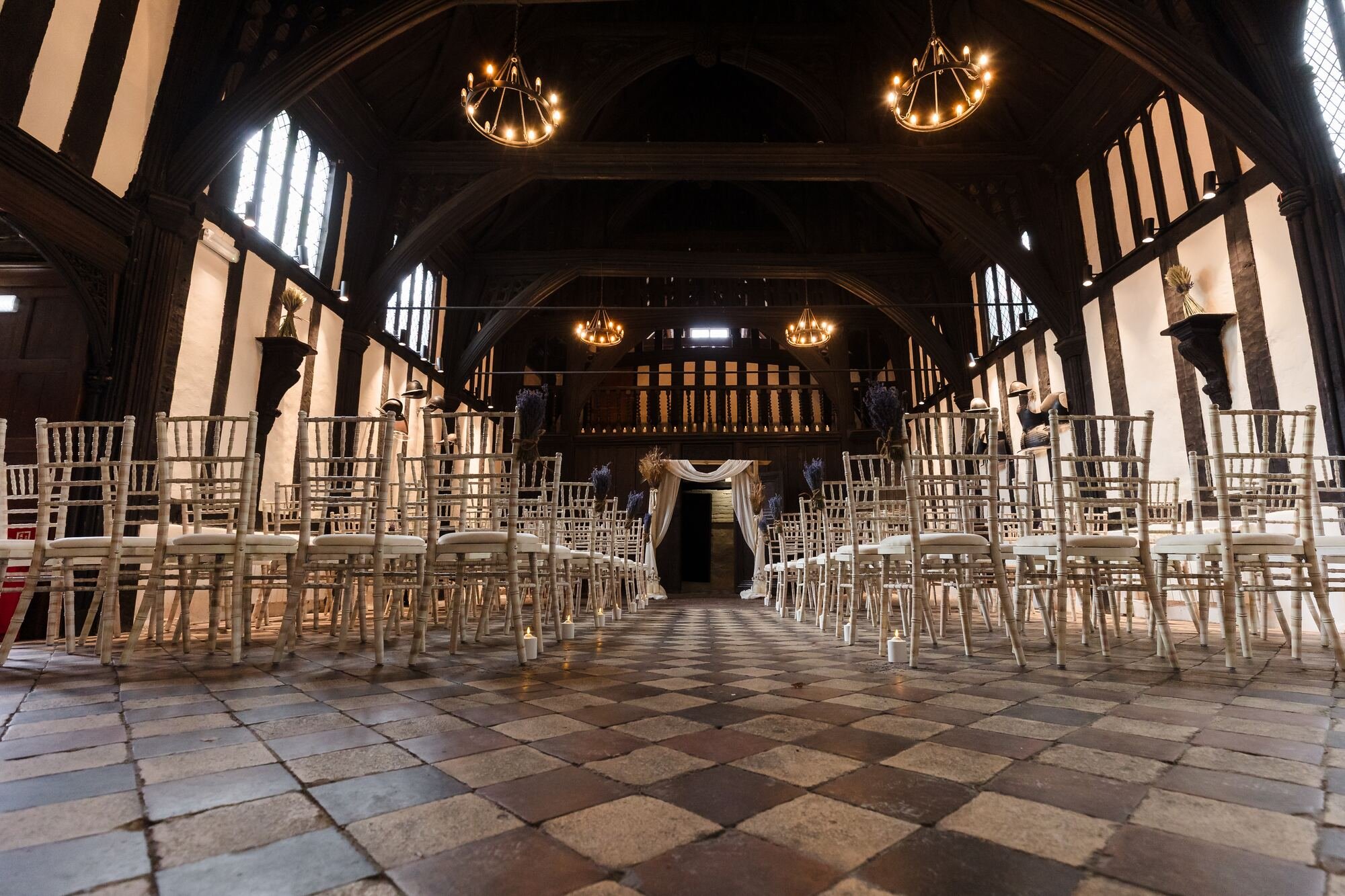 Great Hall at The Commandery, Worcester, set for a ceremony with iron chandeliers and a chequered floor, by Once in a Lifetime Photography