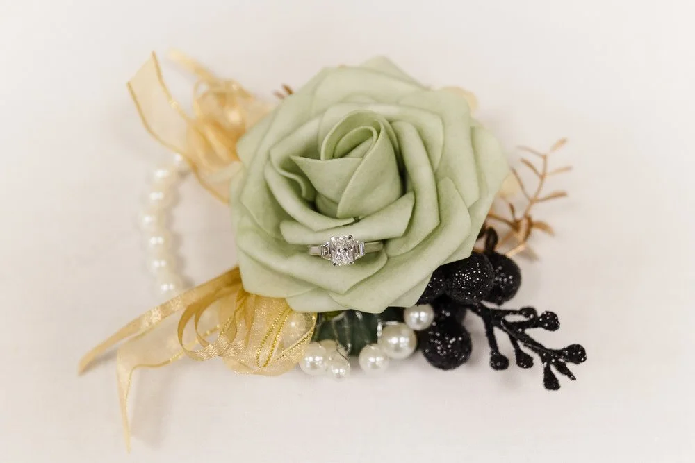 Engagement ring on sage green rose with gold ribbon and pearl details, wedding detail photography by Once in a Lifetime Photography