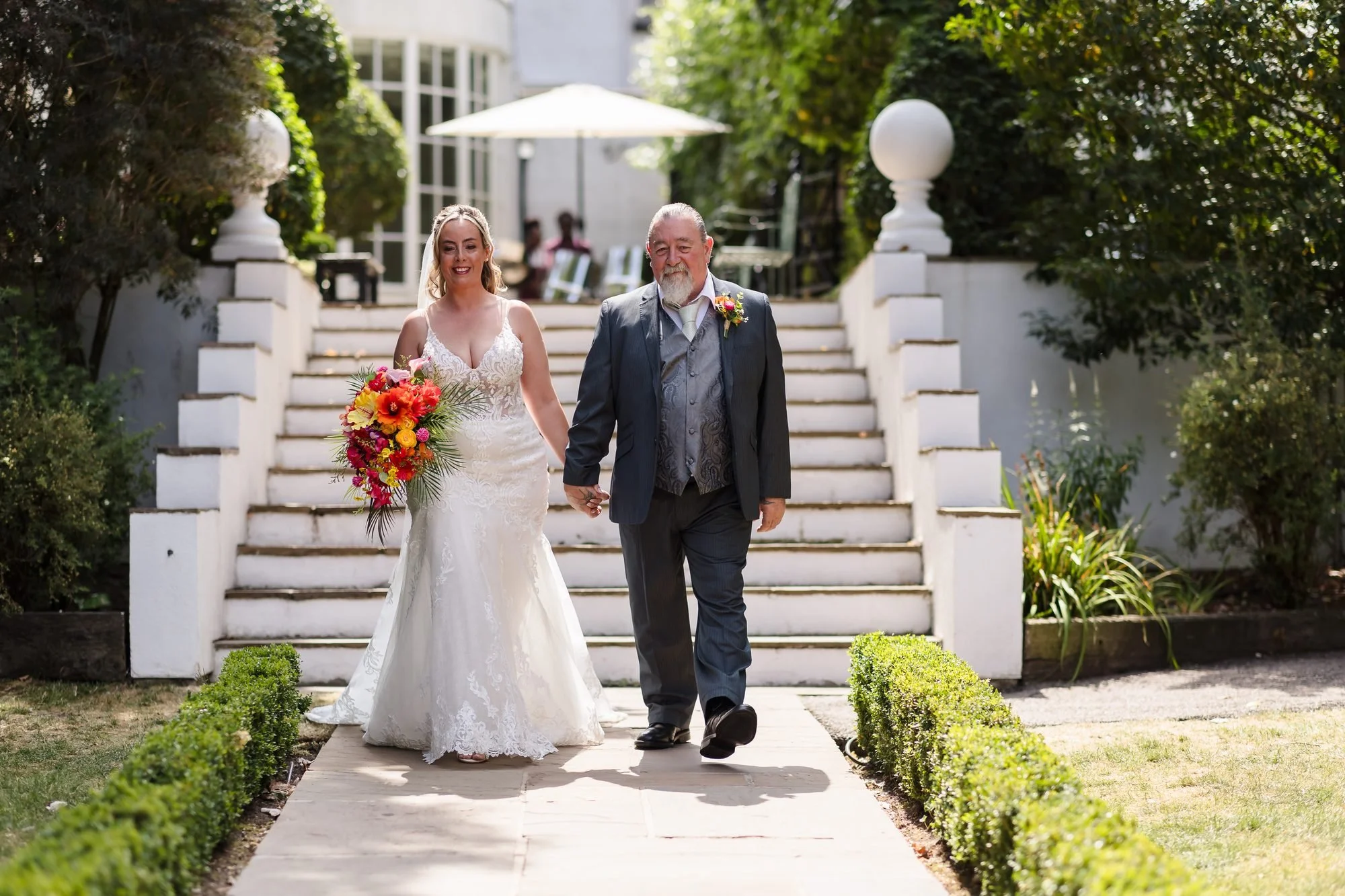 Bride walking down the outdoor aisle with her father at Warwick House, Southam