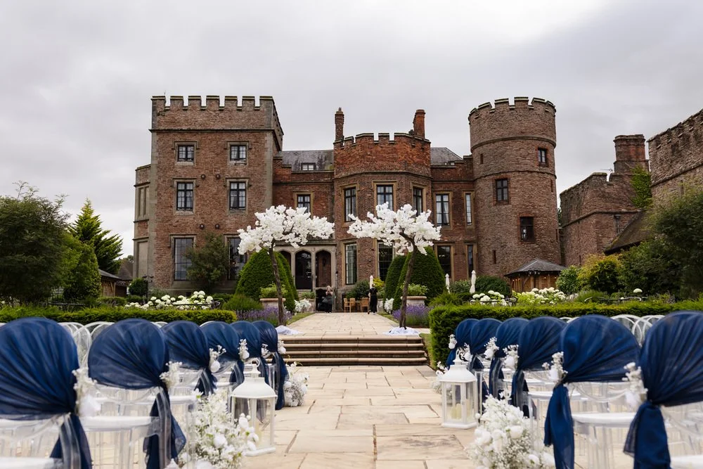 Wedding ceremony aisle at Rowton Castle looking towards the castle, framed by blossom trees