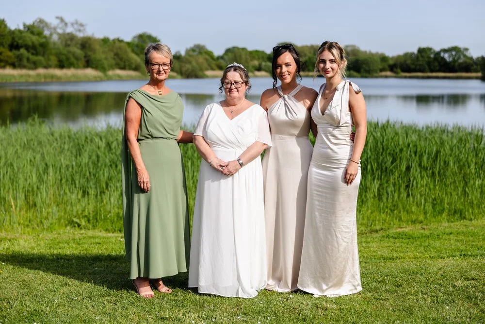 Bride with bridal party posing beside the lake at De Vere Cotswold Water Park