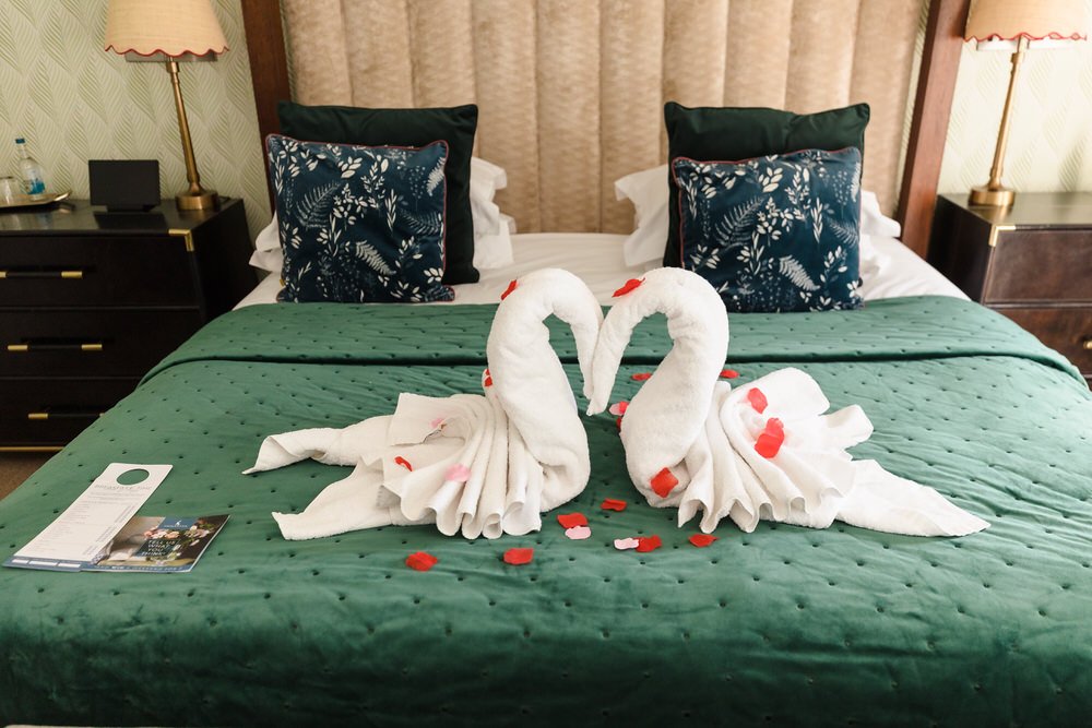 Romantic honeymoon room setup with towel swans on the bed at Hogarths Hotel wedding venue.