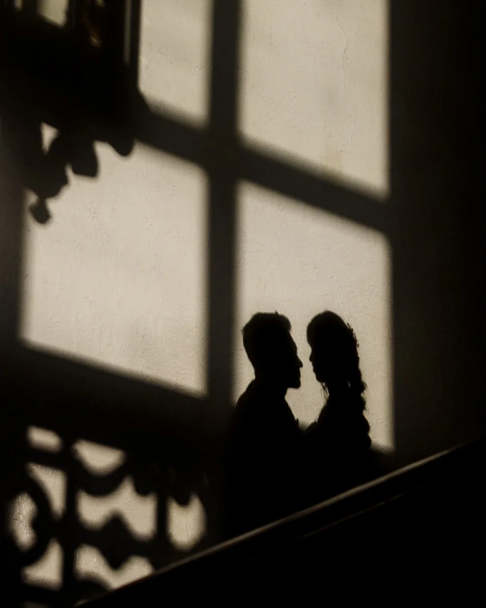 Silhouette of Christine and Greg framed by window light on the staircase at The Welcombe Hotel, Warwickshire.