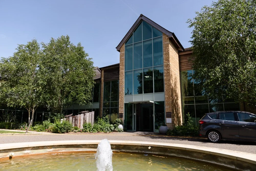 Glass-fronted entrance and fountain at De Vere Cotswold Water Park Hotel