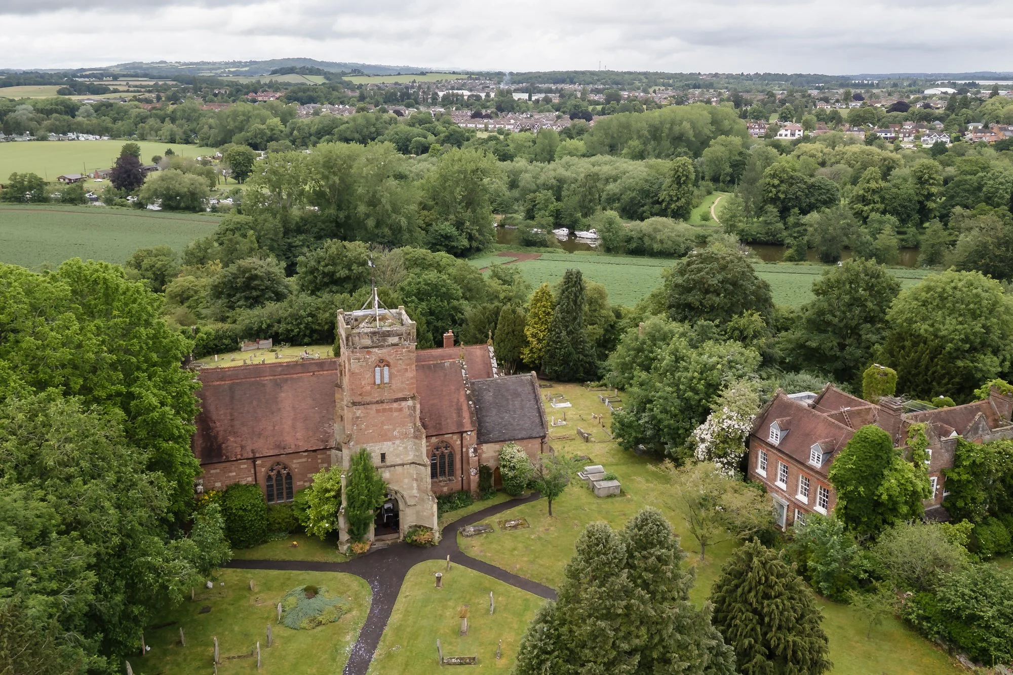 Aerial drone view of St Bartholomew's Church and grounds in Stourport-on-Severn, with the River Severn beyond.