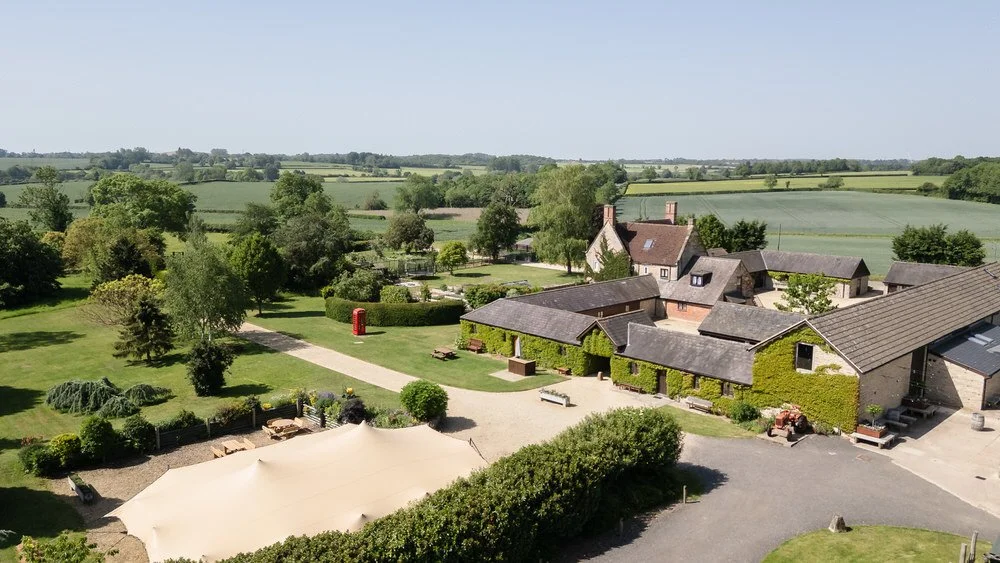 Aerial view of Huntsmill Farm's ivy-covered barns and courtyard, surrounded by open Buckinghamshire countryside.