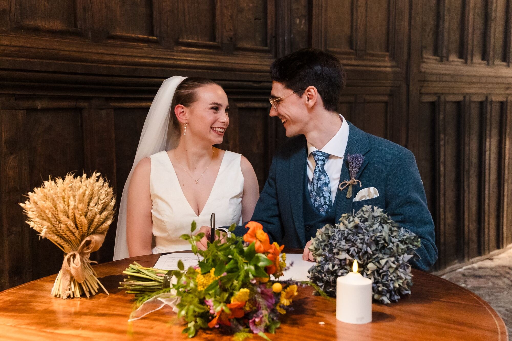Isabelle and Chris smiling at each other while signing the register at The Commandery, Worcester, by Once in a Lifetime Photography