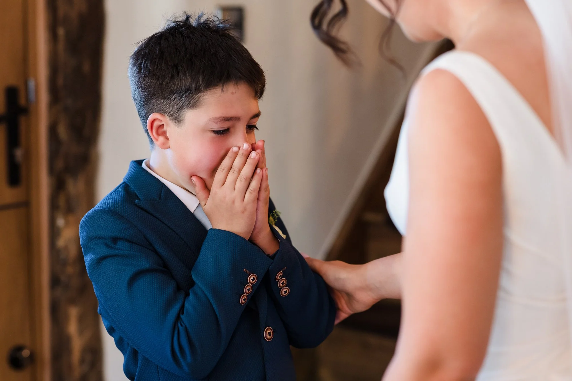Young page boy overcome with emotion holding the bride's hand, candid wedding photography capturing genuine moments