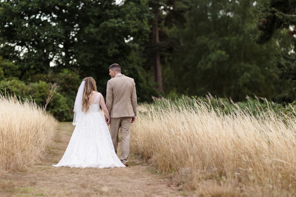 Birmingham wedding photographer captures bride and groom walking through golden wheat fields at Hogarths Stone Manor