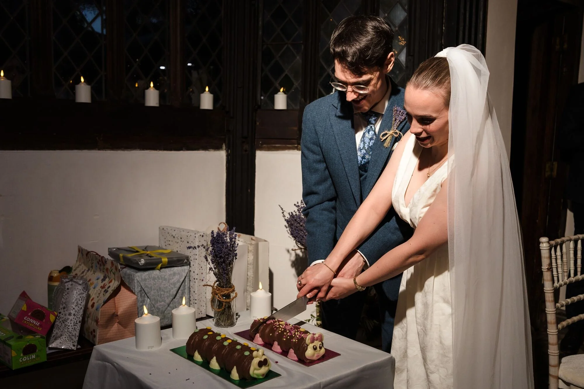 Isabelle and Chris cutting their caterpillar cakes during the evening reception at The Commandery, Worcester, by Once in a Lifetime Photography