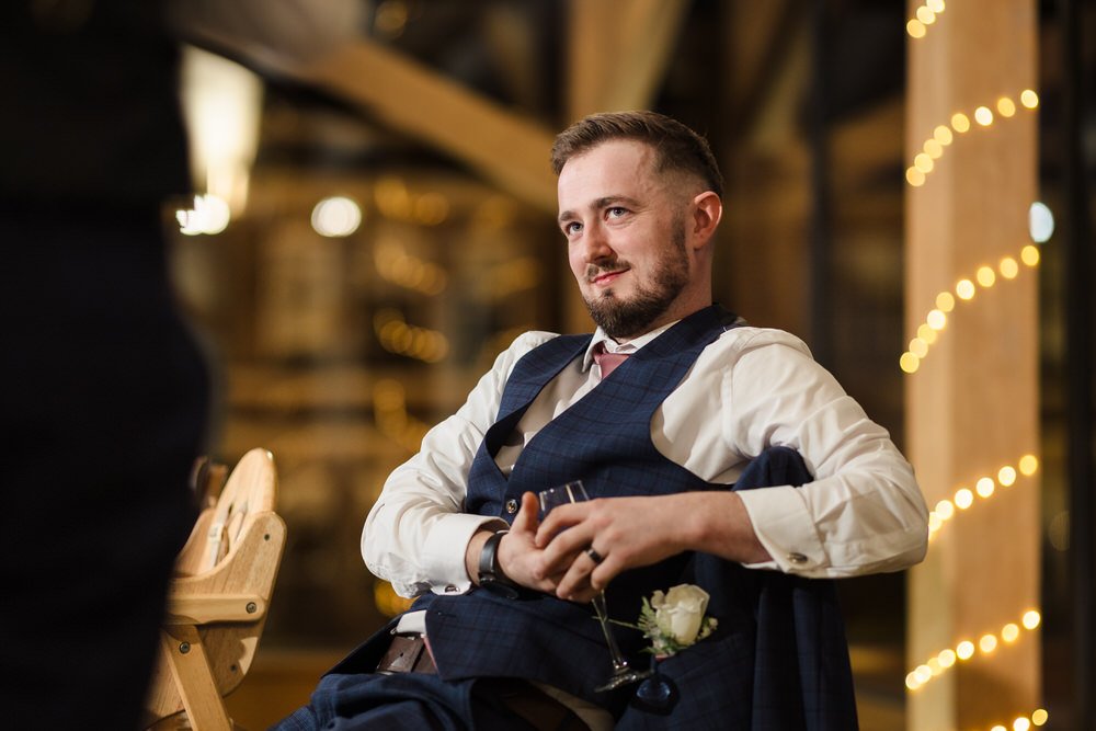 Groom listening to speeches during Bredenbury Court Barns wedding reception