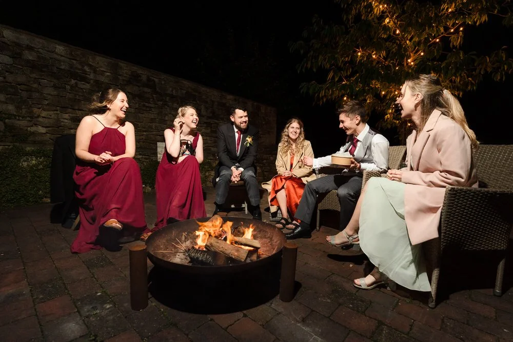 wedding guests sitting outside beside the fire pit