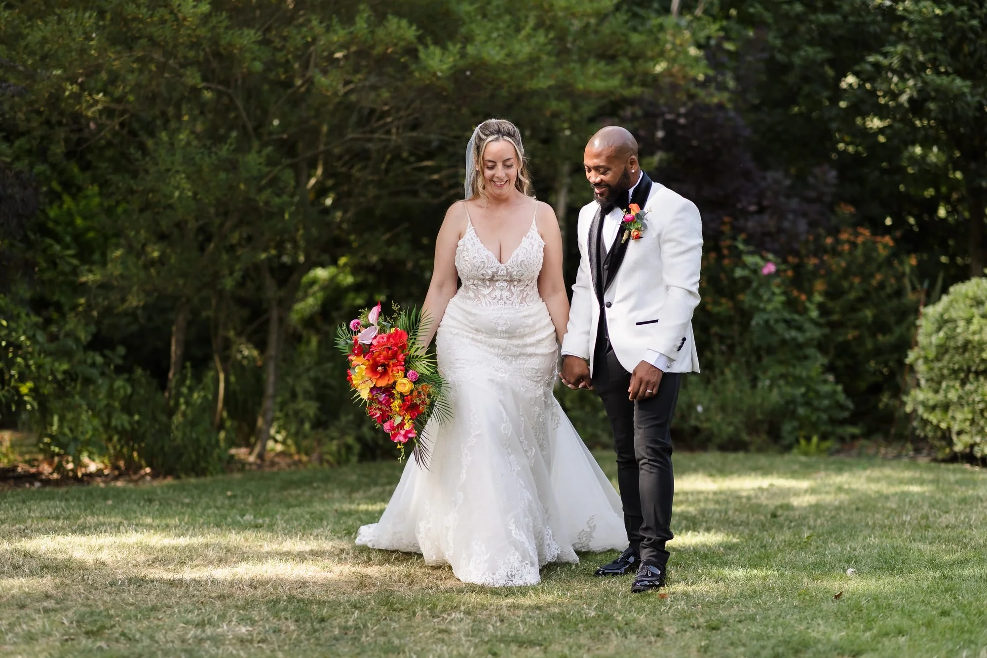 Angela and Tafarie laughing as they walk hand in hand across the lawn during their portraits at Warwick House