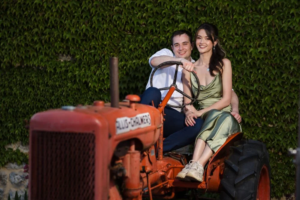 Wedding guests posing on the vintage tractor at Huntsmill Farm in front of the ivy-covered wall.