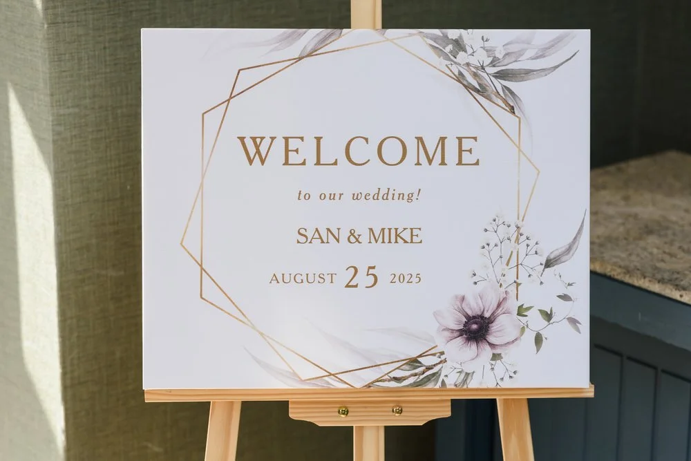 Wedding welcome sign on an easel reading San and Mike, August 25 2025, with gold geometric frame and floral details at Hogarths Hotel Solihull — wedding photography by Once in a Lifetime Photography, Worcestershire
