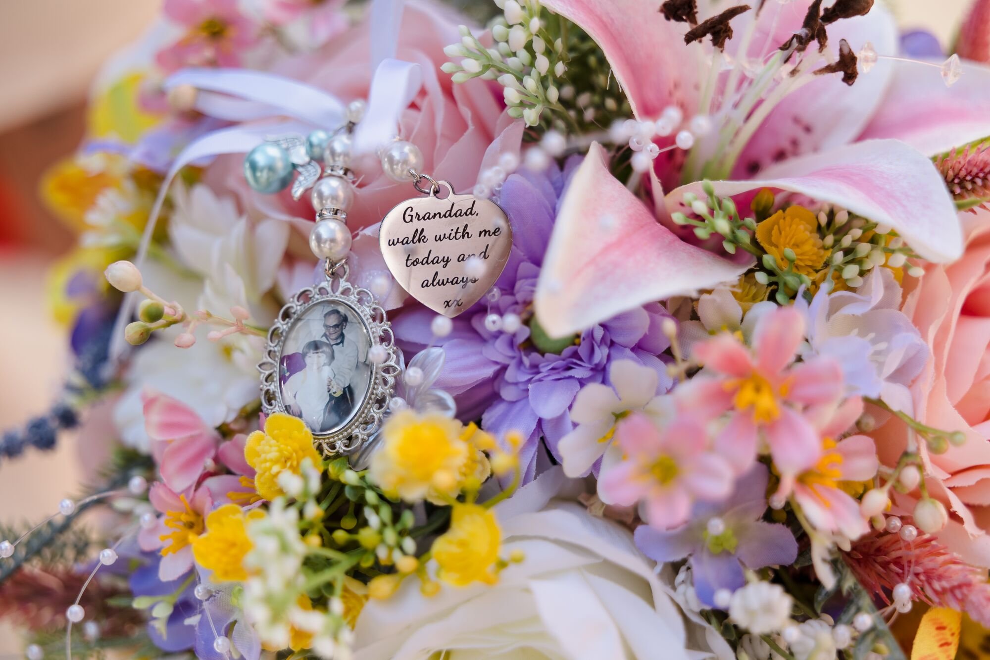 A memorial charm and photograph pinned into the bride's bouquet at Lichfield Registry Office, wedding photography by Once in a Lifetime Photography.