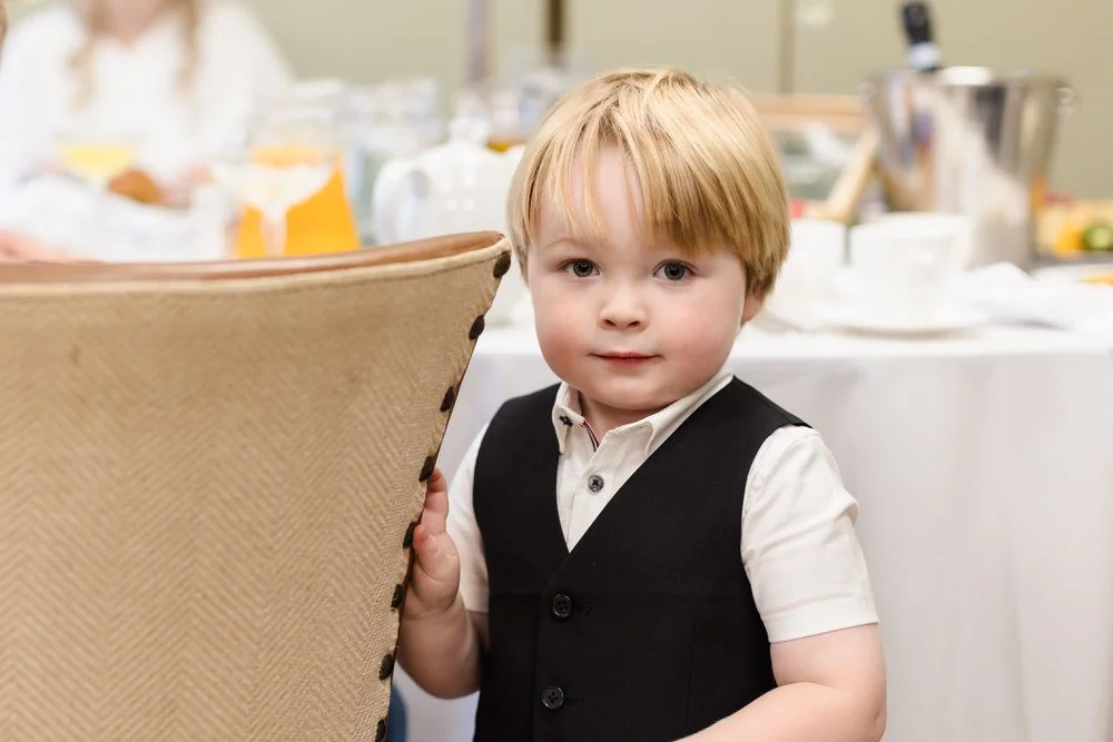 Young page boy at wedding reception dinner table, candid children photography at Arley House by Once in a Lifetime Photography