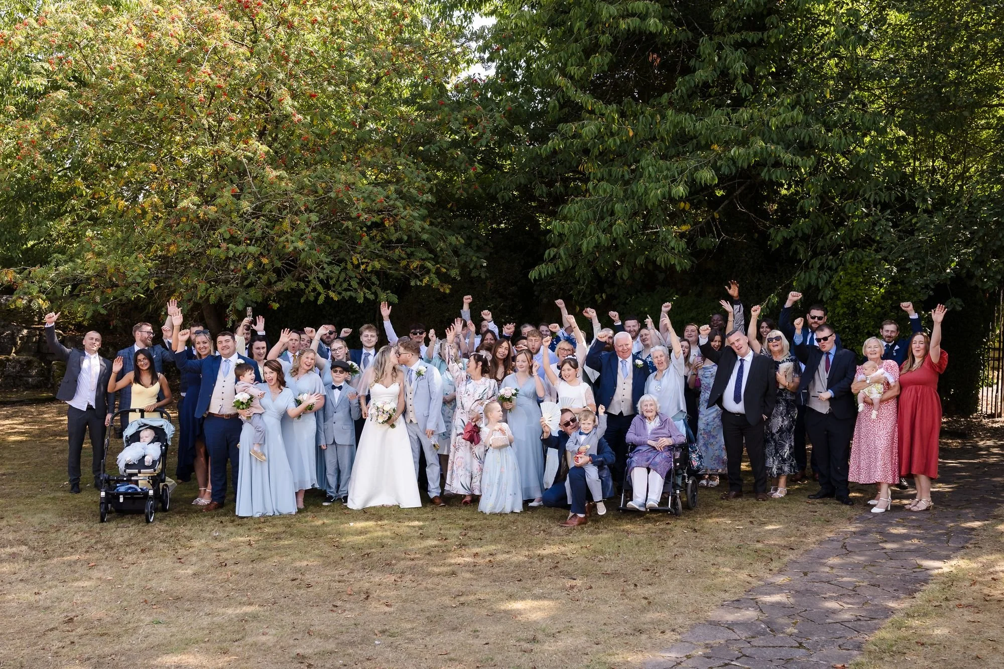 Cheryl and Josh with all their wedding guests cheering with arms raised under the trees at Hogarths Stone Manor