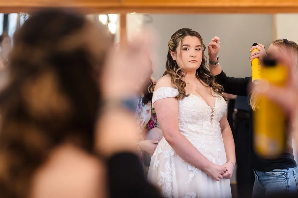 Bride getting ready with hairspray during wedding preparations at Bredenbury Court Barns