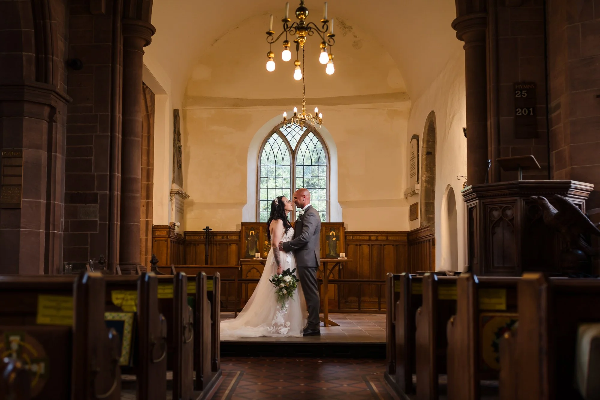 Bride and groom embracing at the altar of St Bartholomew's Church, Stourport-on-Severn, framed by the pews.