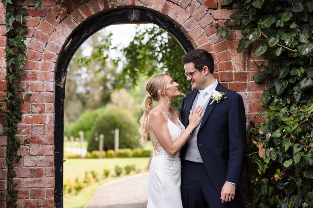 Romantic couple portrait at Bredenbury Court brick archway with countryside views in Herefordshire