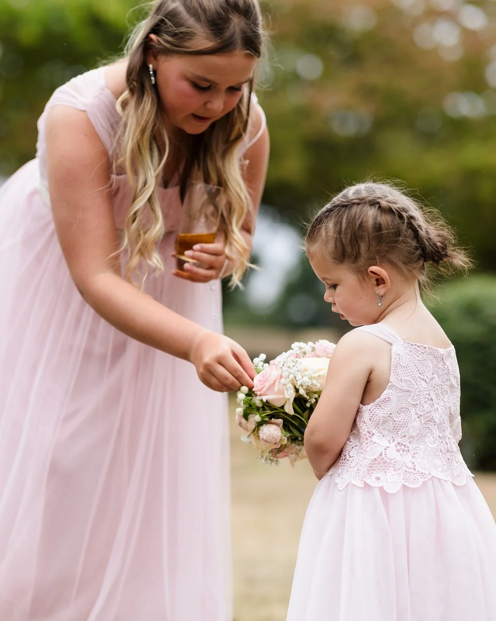 Bridesmaid and flower girl with bouquet in Hogarths Stone Manor grounds, candid wedding photography